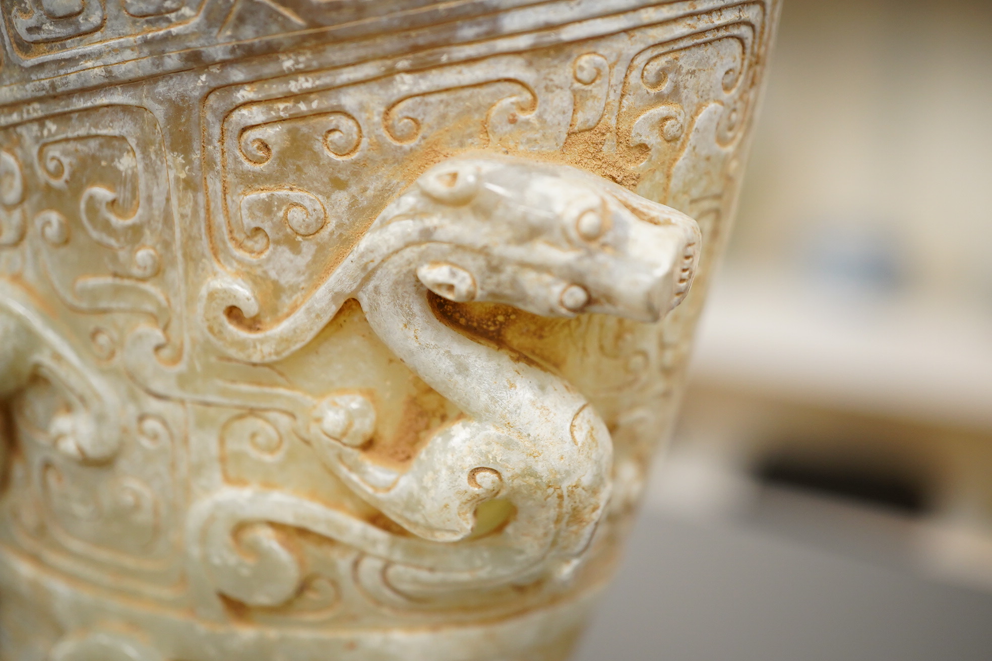 A large Chinese archaistic pale celadon and calcified jade rhyton